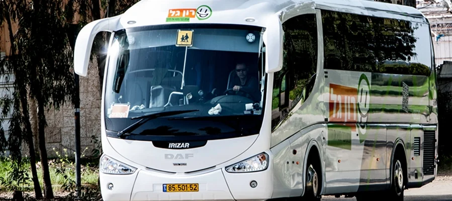 אוטובוס DAF Irizar לבן עם כיתוב בעברית בחזיתו נוסע ברחוב; הנהג נראה מבעד לשמשה הקדמית.